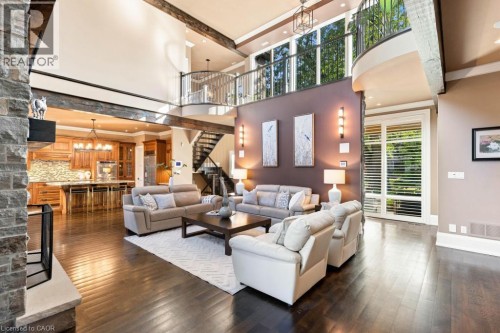 Spacious living area featuring high ceilings, exposed architectural beams, dark wood-finish flooring, and a stone-clad fireplace - 253 Rossmore Boulevard, Burlington, ON - Indoor Photo Showing Living Room