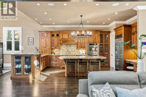 Gourmet kitchen featuring wood cabinetry, stainless steel appliances, a multi-toned tile backsplash, and stone countertops - 253 Rossmore Boulevard, Burlington, ON - Indoor