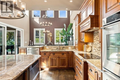 Kitchen featuring wood-finish flooring, abundant cabinetry, stone countertops, and stainless steel appliances - 253 Rossmore Boulevard, Burlington, ON - Indoor Photo Showing Kitchen With Upgraded Kitchen