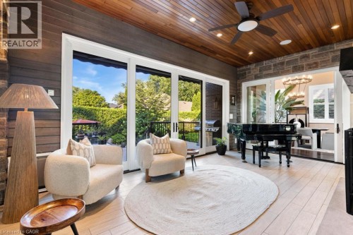 Wood-finish ceiling with recessed lighting and a ceiling fan, stone accent wall, light wood-finish flooring, and large sliding glass doors - 253 Rossmore Boulevard, Burlington, ON - Outdoor With Deck Patio Veranda With Exterior