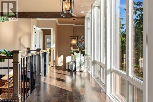 Wood-finish flooring, exposed wood beams, wrought iron and wood balusters, and expansive windows - 253 Rossmore Boulevard, Burlington, ON - Indoor Photo Showing Other Room