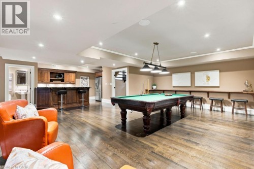 Hardwood-finish flooring, recessed lighting, built-in wet bar with wood cabinetry, and a dedicated billiards area with a hanging fixture - 253 Rossmore Boulevard, Burlington, ON - Indoor Photo Showing Other Room