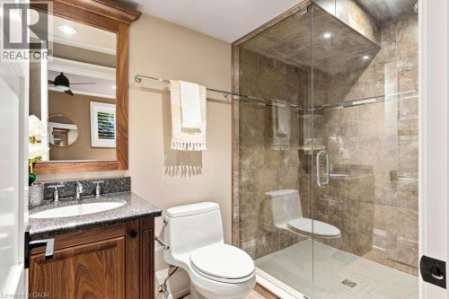 Wood-finish vanity with a dark speckled countertop, recessed sink, and chrome-finish faucet - 253 Rossmore Boulevard, Burlington, ON - Indoor Photo Showing Bathroom