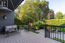 Composite deck with black metal railings, leading to a lower patio area featuring gravel and pavers - 