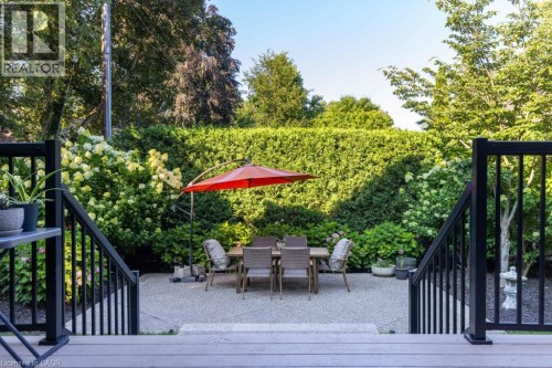 Expansive patio with textured concrete, framed by lush perimeter plantings and a mature hedge - 253 Rossmore Boulevard, Burlington, ON - Outdoor