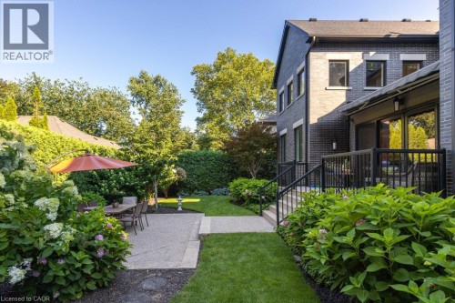 Expansive rear yard featuring a concrete patio, landscaped garden beds, and a manicured lawn - 253 Rossmore Boulevard, Burlington, ON - Outdoor