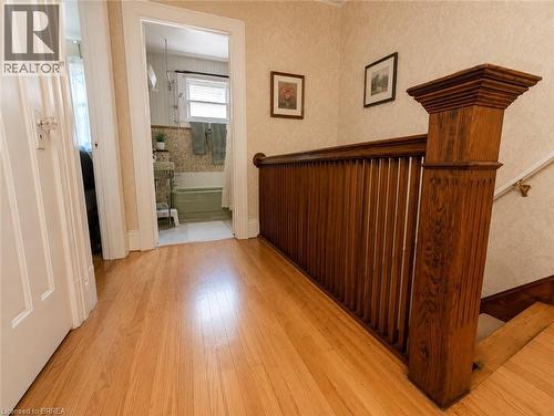Original hardwood floors on the second floor landing, complemented by a substantial wood newel post and classic balusters, add warmth and character. - 49 Palmerston Avenue, Brantford, ON - Indoor Photo Showing Other Room