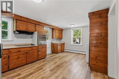 Kitchen featuring extensive wood cabinetry, wood-finish flooring, white tiled backsplash, built-in oven, and natural light from multiple windows - 41 Mill Street, Mississauga, ON - Indoor Photo Showing Kitchen