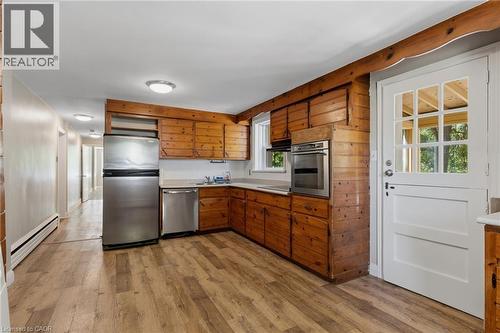 Kitchen featuring wood-paneled walls, wood-finish flooring, stainless steel appliances, and a Dutch door with glass panes - 41 Mill Street, Mississauga, ON - Indoor Photo Showing Kitchen