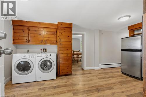 Laundry area featuring wood-finish flooring, built-in wooden cabinetry, and a washer and dryer - 41 Mill Street, Mississauga, ON - Indoor Photo Showing Laundry Room