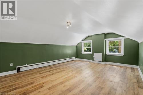 Bright room featuring wood-finish flooring, two windows with white trim, and a multi-bulb ceiling light fixture - 41 Mill Street, Mississauga, ON - Indoor Photo Showing Other Room