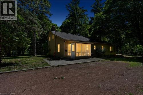 Property exterior featuring a screened porch, multiple windows, a shingled roof, a paved patio, and mature trees - 41 Mill Street, Mississauga, ON - Outdoor