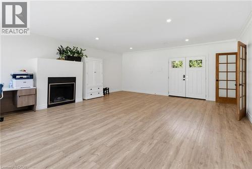 Recessed lighting, crown molding, wood-finish flooring, a built-in fireplace, and double French doors with transom windows - 21 Kerman Avenue, Grimsby, ON 