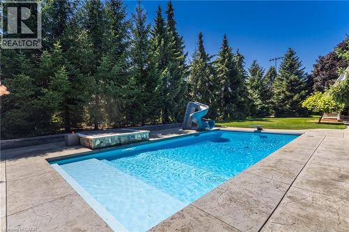 Resort-style swimming pool featuring crystal-clear water, integrated spa with cascading water feature, and expansive concrete decking - 21 Kerman Avenue, Grimsby, ON 