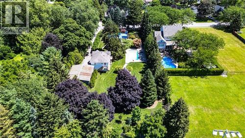 Sprawling residential estate set on manicured grounds featuring mature landscaping, mixed evergreen and deciduous trees, and expansive lawn - 21 Kerman Avenue, Grimsby, ON 