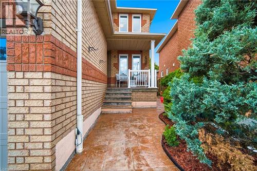 Brick exterior featuring contrasting brick banding, a covered porch, a stamped concrete pathway, and established landscaping - 5184 Red Brush Drive, Mississauga, ON - Outdoor