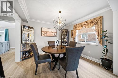 Spacious dining area featuring wood-finish flooring, a contemporary geometric chandelier, and crown molding - 5184 Red Brush Drive, Mississauga, ON - Indoor Photo Showing Dining Room
