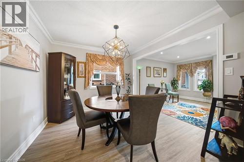 Dining area featuring wood-finish flooring, a contemporary geometric chandelier, and crown molding - 5184 Red Brush Drive, Mississauga, ON - Indoor Photo Showing Dining Room