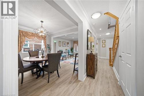 Foyer and dining area with wood-finish flooring, white trim, recessed lighting, and a prominent geometric chandelier - 5184 Red Brush Drive, Mississauga, ON - Indoor Photo Showing Dining Room