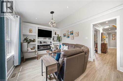 Living area featuring wood-finish flooring and a built-in media center with shelving and an electric fireplace - 5184 Red Brush Drive, Mississauga, ON - Indoor