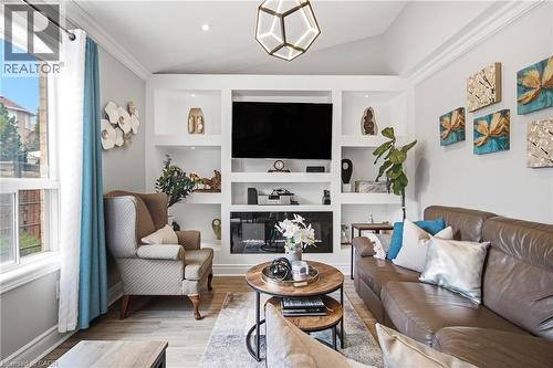 Living area featuring a floor-to-ceiling built-in entertainment unit with shelving and an integrated electric fireplace - 5184 Red Brush Drive, Mississauga, ON - Indoor Photo Showing Living Room