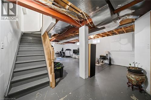 Lower level featuring a staircase with painted treads, wood handrail, exposed ceiling beams, and a concrete floor - 5184 Red Brush Drive, Mississauga, ON - Indoor Photo Showing Basement