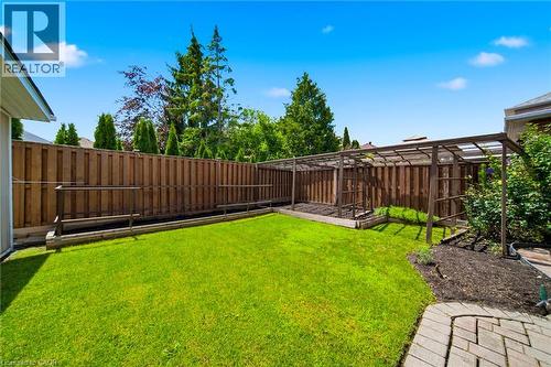 Expansive backyard featuring a lush lawn, privacy fencing, a wood pergola structure, and a paver stone patio section - 5184 Red Brush Drive, Mississauga, ON - Outdoor
