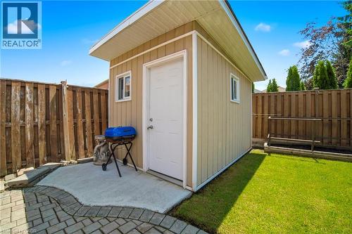 Freestanding storage shed with beige vertical siding and white trim, featuring a white access door and two windows - 5184 Red Brush Drive, Mississauga, ON - Outdoor With Exterior