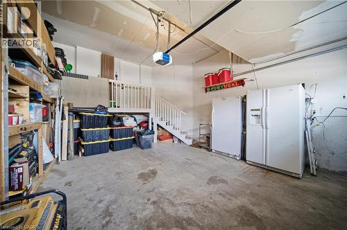 Spacious garage with concrete flooring, integrated shelving, and a white staircase leading to an upper level - 5184 Red Brush Drive, Mississauga, ON - Indoor Photo Showing Garage