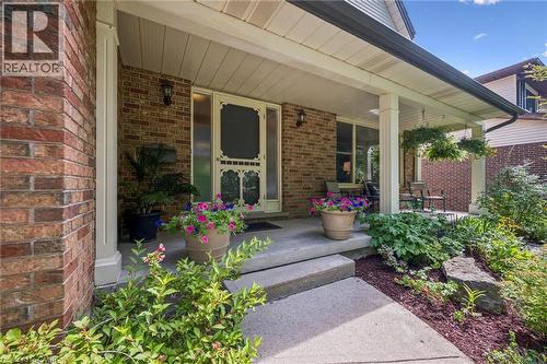 Brick exterior featuring a covered porch, concrete steps, and a decorative screen door - 119 Sandy Ridge Place, Waterloo, ON - Outdoor With Deck Patio Veranda