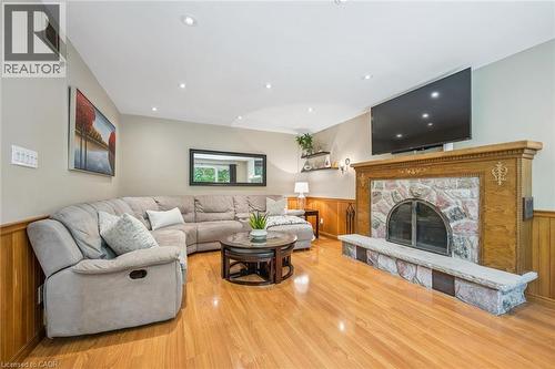 Recessed lighting, wood-finish flooring, stone fireplace with a wood mantel, and wood paneling - 119 Sandy Ridge Place, Waterloo, ON - Indoor Photo Showing Living Room With Fireplace