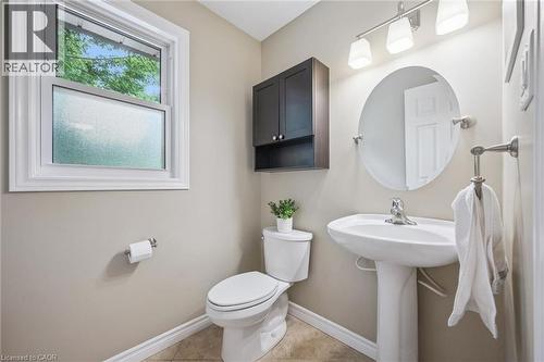 Pedestal sink with single-handle faucet, round wall mirror, track lighting fixture, and a built-in wall cabinet with shelving - 119 Sandy Ridge Place, Waterloo, ON - Indoor Photo Showing Bathroom