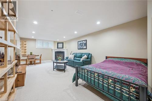 Recessed lighting, white window shutters, a white fireplace with a dark insert, light-toned carpeting, and a built-in wooden shelving unit - 119 Sandy Ridge Place, Waterloo, ON - Indoor