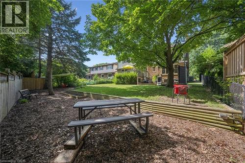 Expansive backyard featuring a manicured lawn, established trees, and wood fencing - 119 Sandy Ridge Place, Waterloo, ON - Outdoor With Deck Patio Veranda