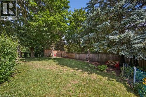 Expansive lawn area surrounded by mature trees, privacy fencing, and garden beds - 119 Sandy Ridge Place, Waterloo, ON - Outdoor