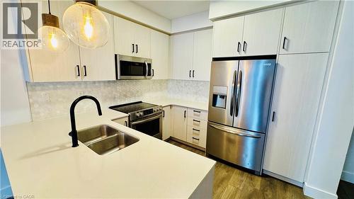 Contemporary kitchen featuring light wood-finish cabinetry, stainless steel appliances, white countertops, and a patterned tile backsplash - 1159 Lloyd Landing, Milton, ON - Indoor Photo Showing Kitchen With Double Sink With Upgraded Kitchen