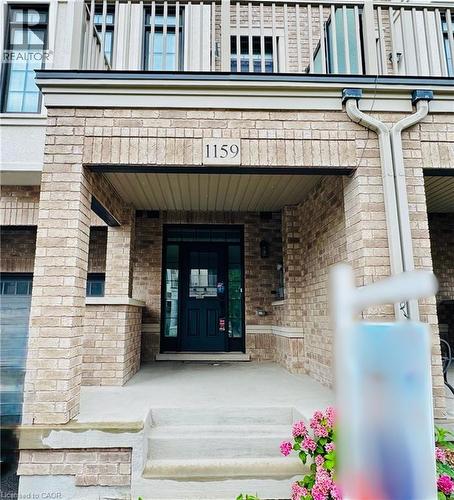 Brick facade with a dark-paneled entry door, concrete steps, and an upper-level balcony with white railings - 1159 Lloyd Landing, Milton, ON - Outdoor