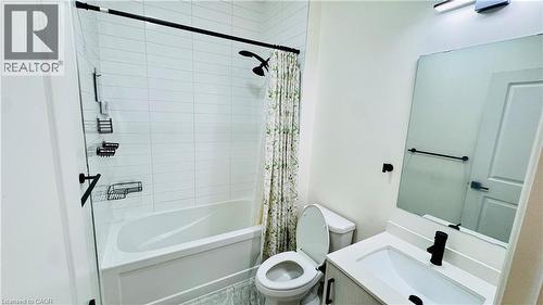 White subway tile shower surround with black fixtures, bathtub, vanity with integrated sink, and wall-mounted mirror - 1159 Lloyd Landing, Milton, ON - Indoor Photo Showing Bathroom