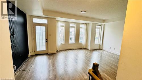 Recessed lighting, wood-finish flooring, a wall-mounted fixture, multiple large windows, and a glass-paneled door - 1159 Lloyd Landing, Milton, ON - Indoor Photo Showing Other Room