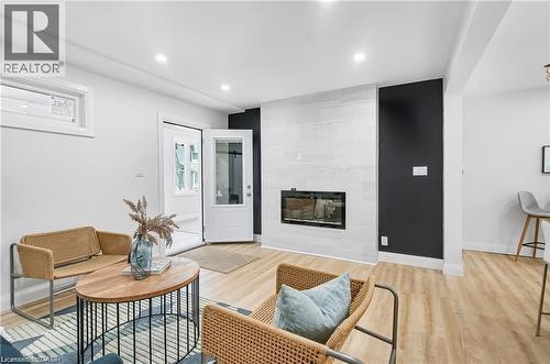 Living space featuring a contemporary fireplace with a light-toned tile surround, light wood-finish flooring, and recessed ceiling lighting - 10 Comet Avenue Unit# #1 (Main), Hamilton, ON - Indoor Photo Showing Living Room With Fireplace