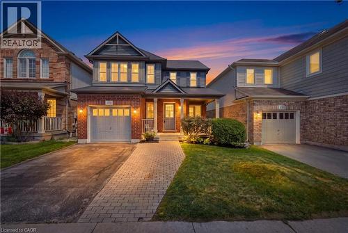 Two-story Colonial residence featuring a welcoming front facade with illuminated multi-pane windows, a brick and siding exterior, a prominent front-gable design, and a circular driveway with permeable - 171 Chase Crescent, Cambridge, ON - Outdoor With Deck Patio Veranda With Facade