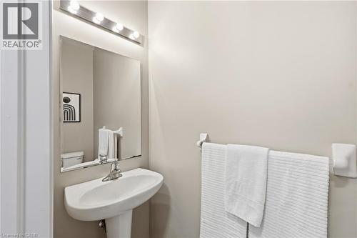 Pedestal sink with chrome faucet, wall-mounted mirror, and vanity lighting - 171 Chase Crescent, Cambridge, ON - Indoor Photo Showing Bathroom