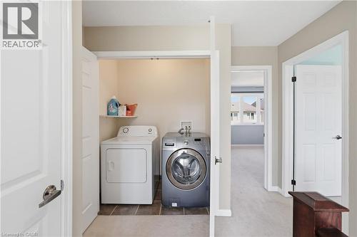 Dedicated laundry room featuring side-by-side washer and dryer with white cabinetry, tile flooring, and ample shelving for storage - 171 Chase Crescent, Cambridge, ON - Indoor Photo Showing Laundry Room