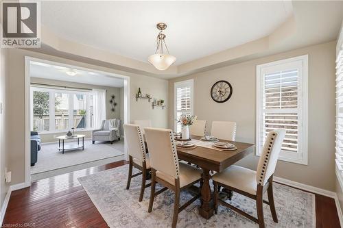 Tray ceiling with a decorative chandelier, wood-finish flooring, and white window shutters - 171 Chase Crescent, Cambridge, ON - Indoor Photo Showing Dining Room