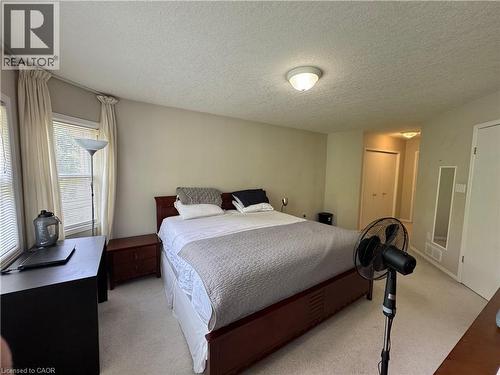 Hardwood-finish bed frame, light neutral wall color, built-in overhead lighting, light-colored carpeting, and window blinds - 720 Brookmill Place, Waterloo, ON - Indoor Photo Showing Bedroom