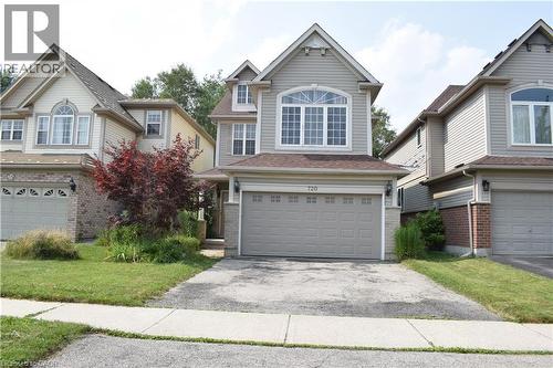 Two-story exterior with light gray siding, an arched window, an integrated garage, and a concrete driveway - 720 Brookmill Place, Waterloo, ON - Outdoor With Facade