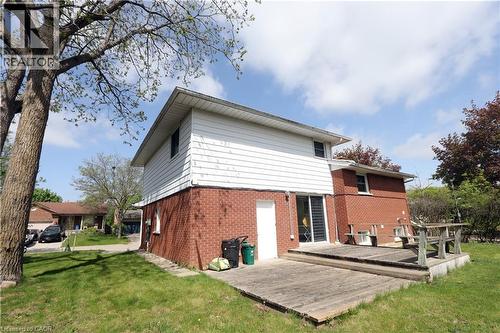 Expansive lawn area with mature trees, brick and siding exterior, sliding glass door access, and a wood deck - 77 Orchard Mill Crescent, Kitchener, ON - Outdoor With Exterior