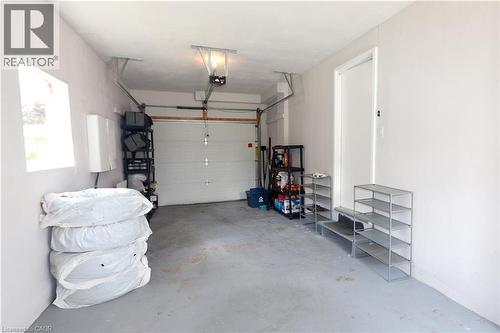 Attached garage with a white overhead door, finished walls, and concrete flooring - 77 Orchard Mill Crescent, Kitchener, ON - Indoor Photo Showing Garage