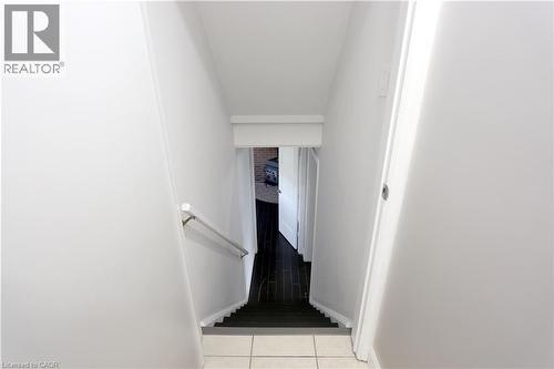Staircase featuring a white handrail, light-toned wall finishes, and dark-toned treads - 77 Orchard Mill Crescent, Kitchener, ON - Indoor Photo Showing Other Room
