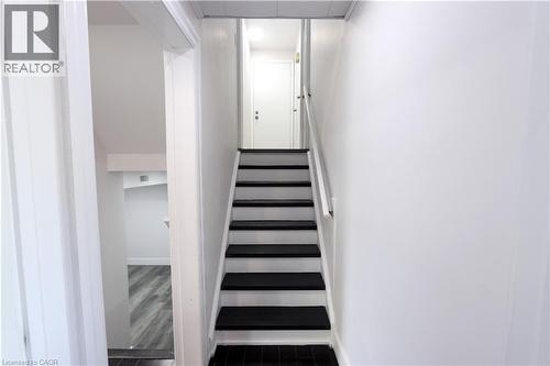 Staircase with contrasting black treads and white risers, framed by a white handrail - 77 Orchard Mill Crescent, Kitchener, ON - Indoor Photo Showing Other Room